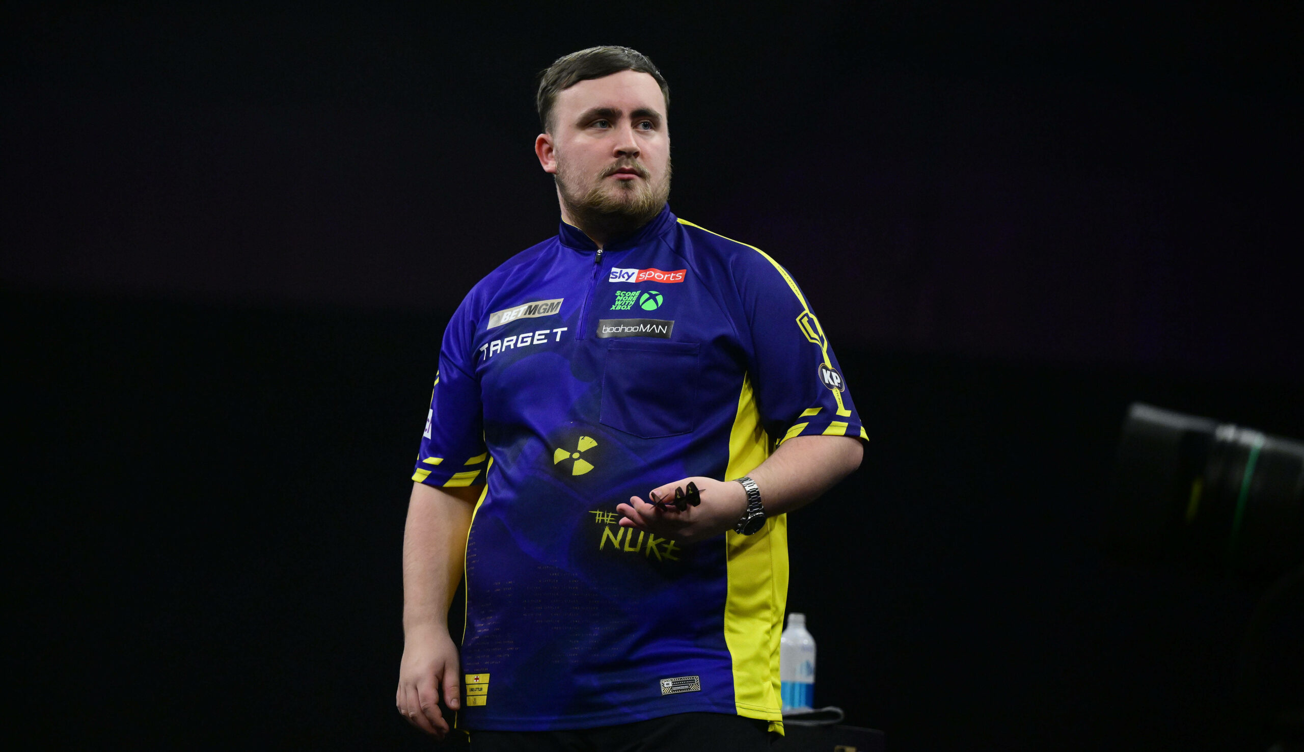 Luke Littler hält seine Darts-Pfeile in der Hand