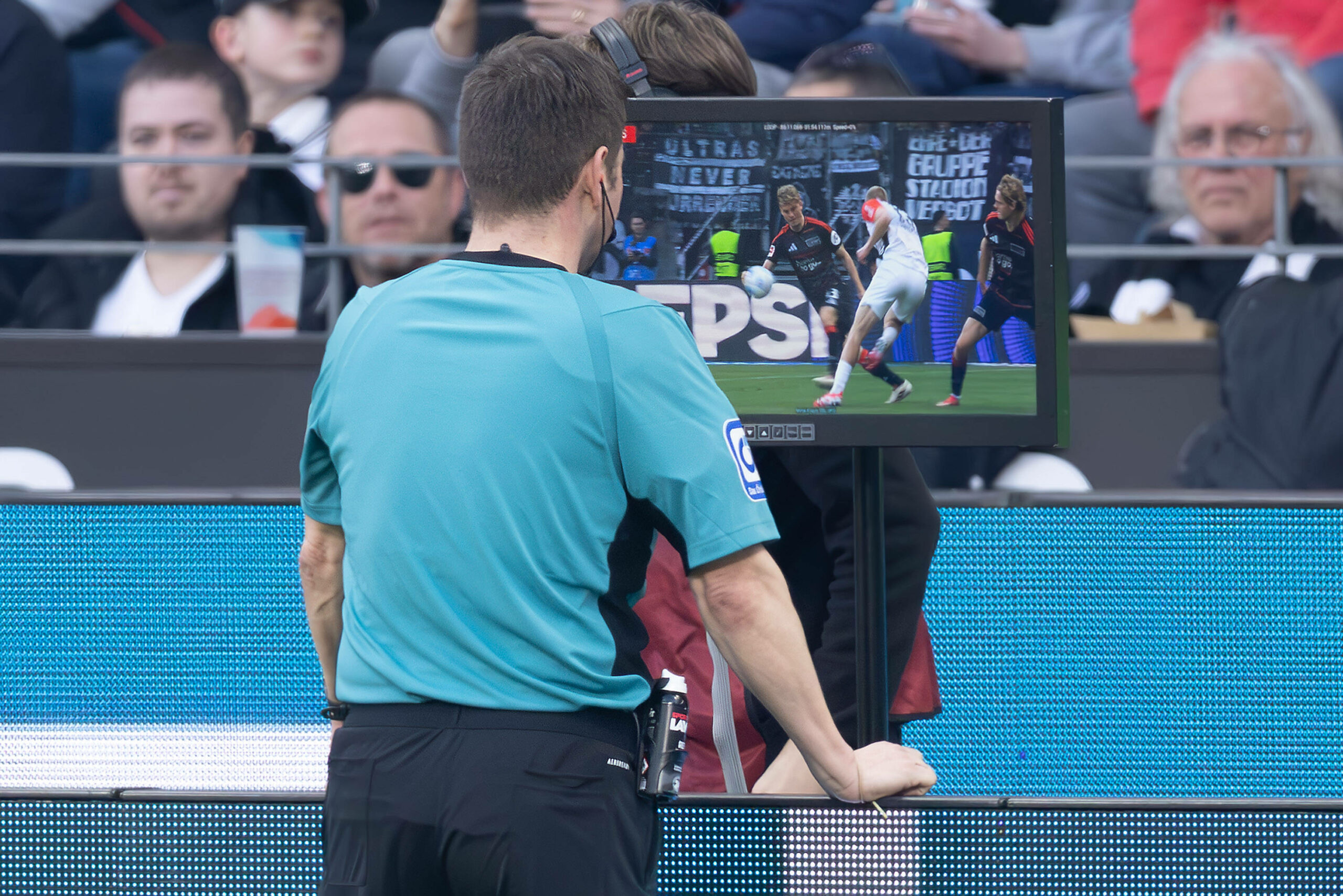 Schiedsrichter schaut sich eine Szene in einem Bundesliga-Spiel auf dem Monitor an.