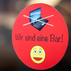 An einer Scheibe der Café-Bar 8tto Grammi weist ein Schild auf das Verbot von Laptops hin.