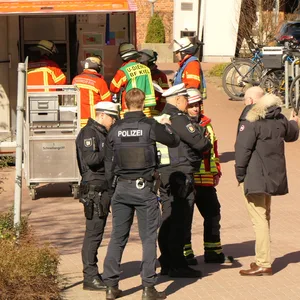 Mitarbeiter von Polizei und Feuerwehr stehen vor dem Verwaltungsgebäude der Uniklinik.