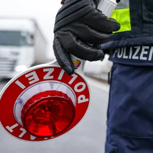Ein Polizist hält eine Polizeikelle für eine Kontrolle an der Autobahn.