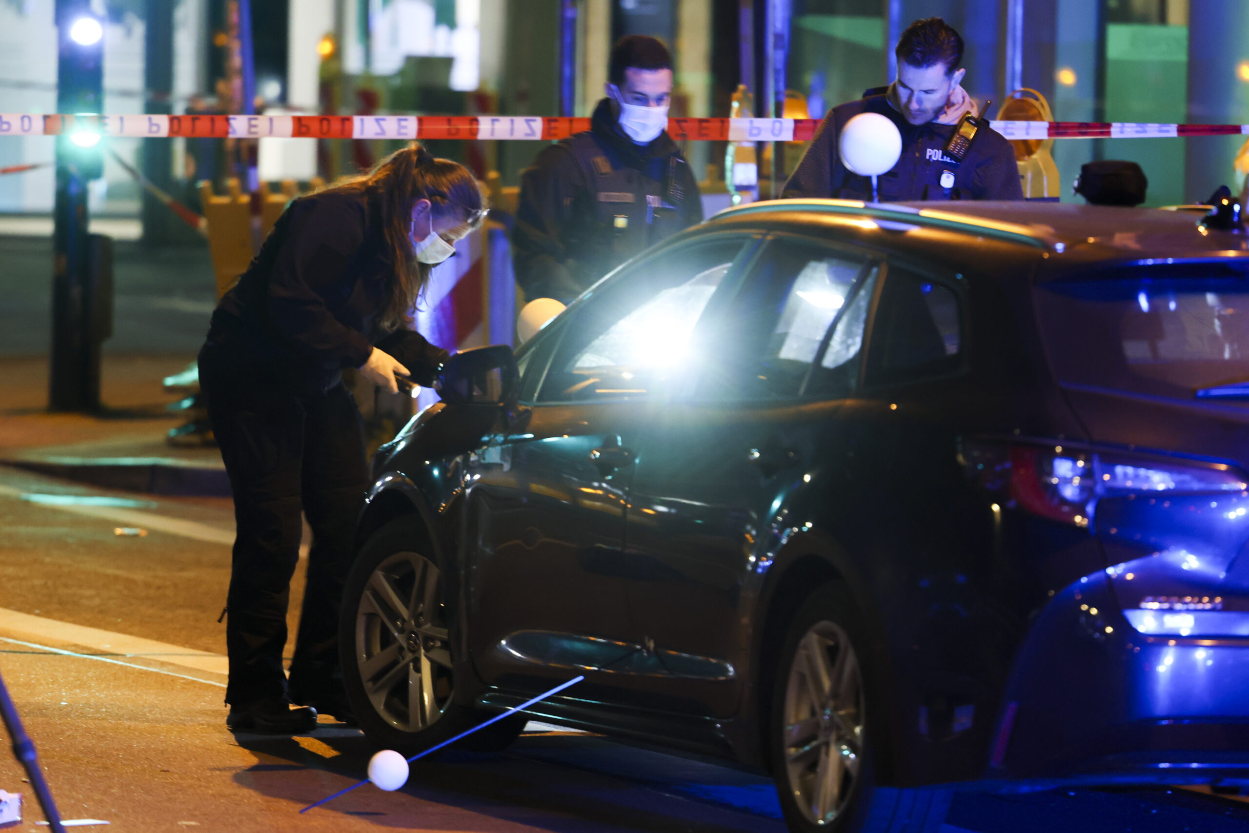 Polizisten mit Taschenlampen an einem Auto