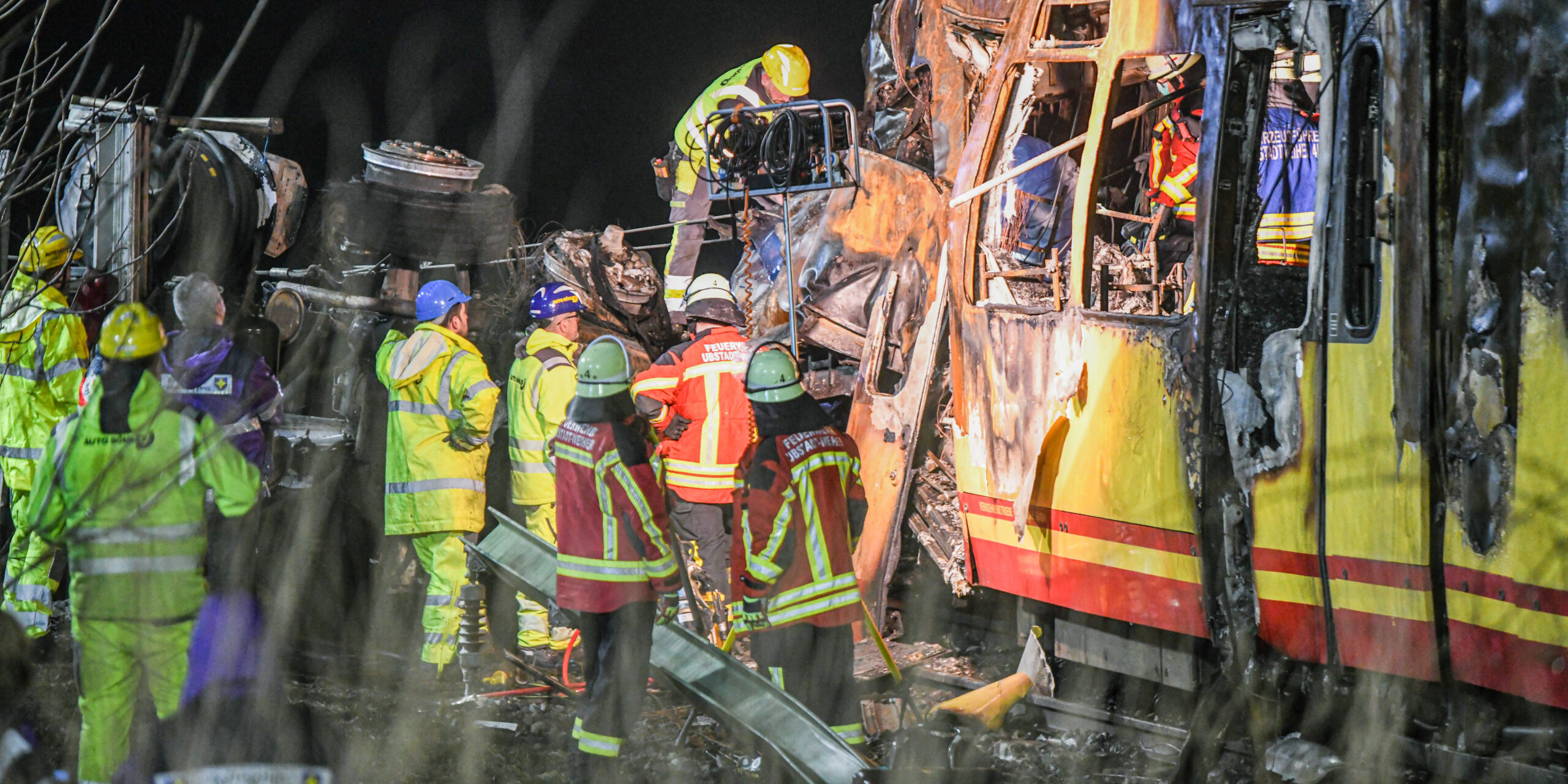 Eine völlig zerstörte Stadtbahn und ein umgekippter Laster mit rund einem Dutzend Feuerwehrleuten