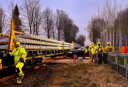 Einsatzkräfte arbeiten am Einsatzort, nachdem eine Autofahrerin am Bahnübergang in einen Arbeitszug gefahren ist.