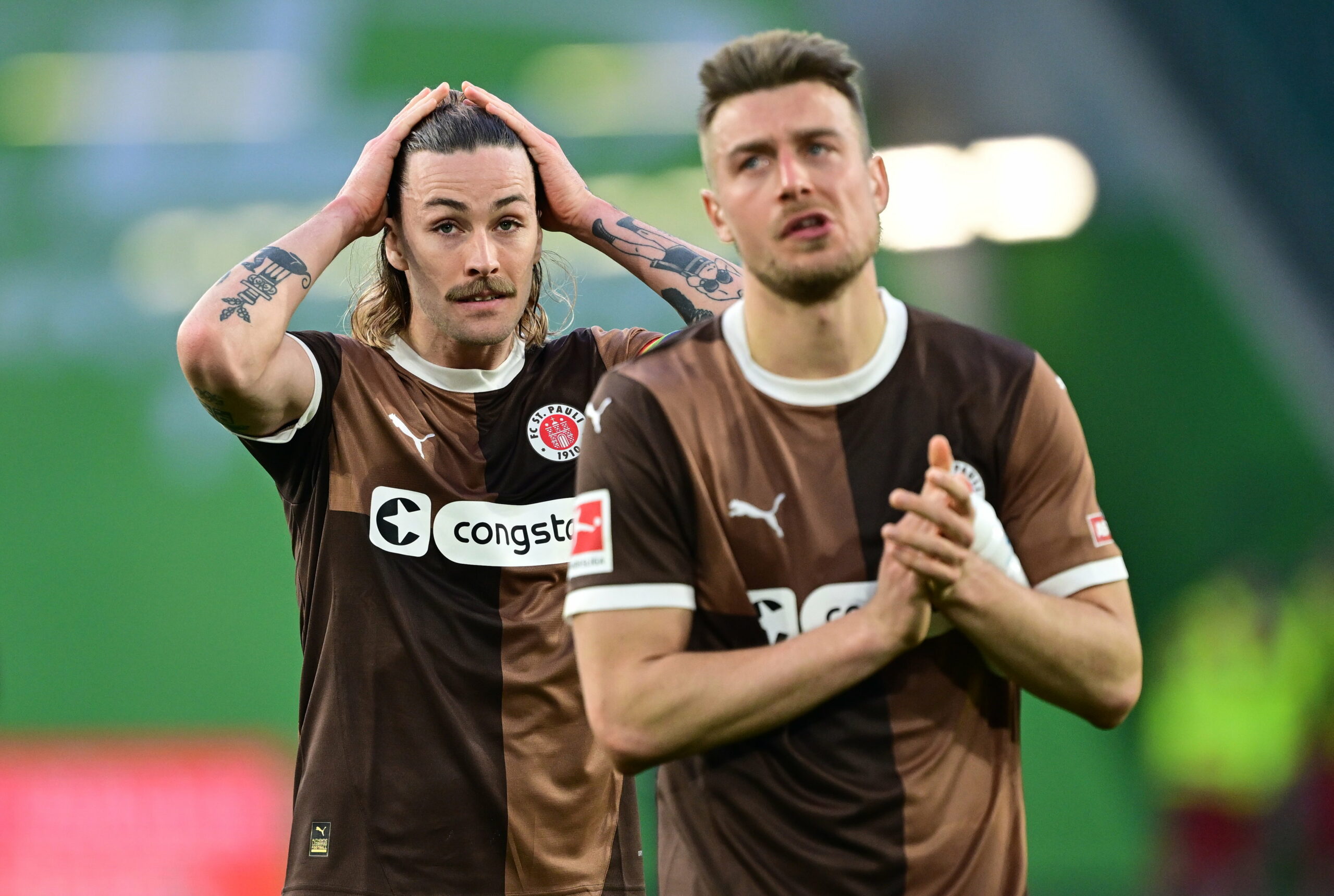 Jackson Irvine geht sich nach dem Schlusspfiff in Wolfsburg durch die Haare, Hauke Wahl applaudiert den Fans.