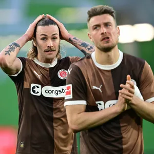Jackson Irvine geht sich nach dem Schlusspfiff in Wolfsburg durch die Haare, Hauke Wahl applaudiert den Fans.