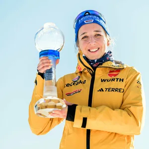 Franziska Preuß hält die Biathlon-Weltcup-Siegertrophäe und lächelt