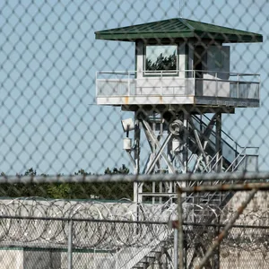 Ein Wachturm hinter einem Gitterzaun in einem Gefängnis.