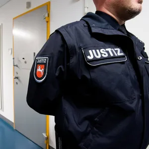 Ein Justizbeamter steht neben Zellen von Gefangenen in einer Justizvollzugsanstalt in Niedersachsen.