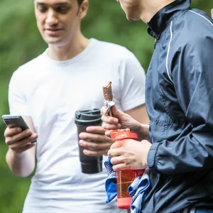 Ein Sportler hält einen Protein-Riegel in der Hand.