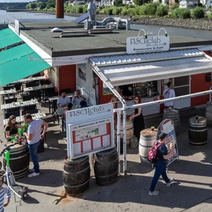 Menschen laufen bei sonnigem Wetter am Fischclub Blankenese vorbei.