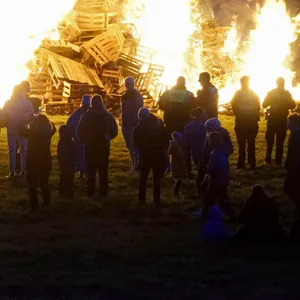 Viele Menschen stehen vor einem riesigen Feuer