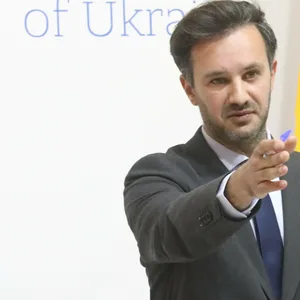 Mann im Anzug vor einer ukrainischen Flagge