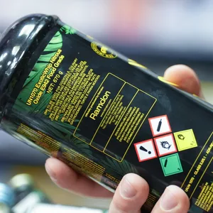 Eine Hand hält eine schwarz/grüne Dose Lachgas hoch.