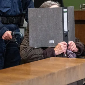 Die 90 Jahre alte Angeklagte wird im Rollstuhl von einer Polizistin in den Sitzungssaal im Landgericht München I geschoben.
