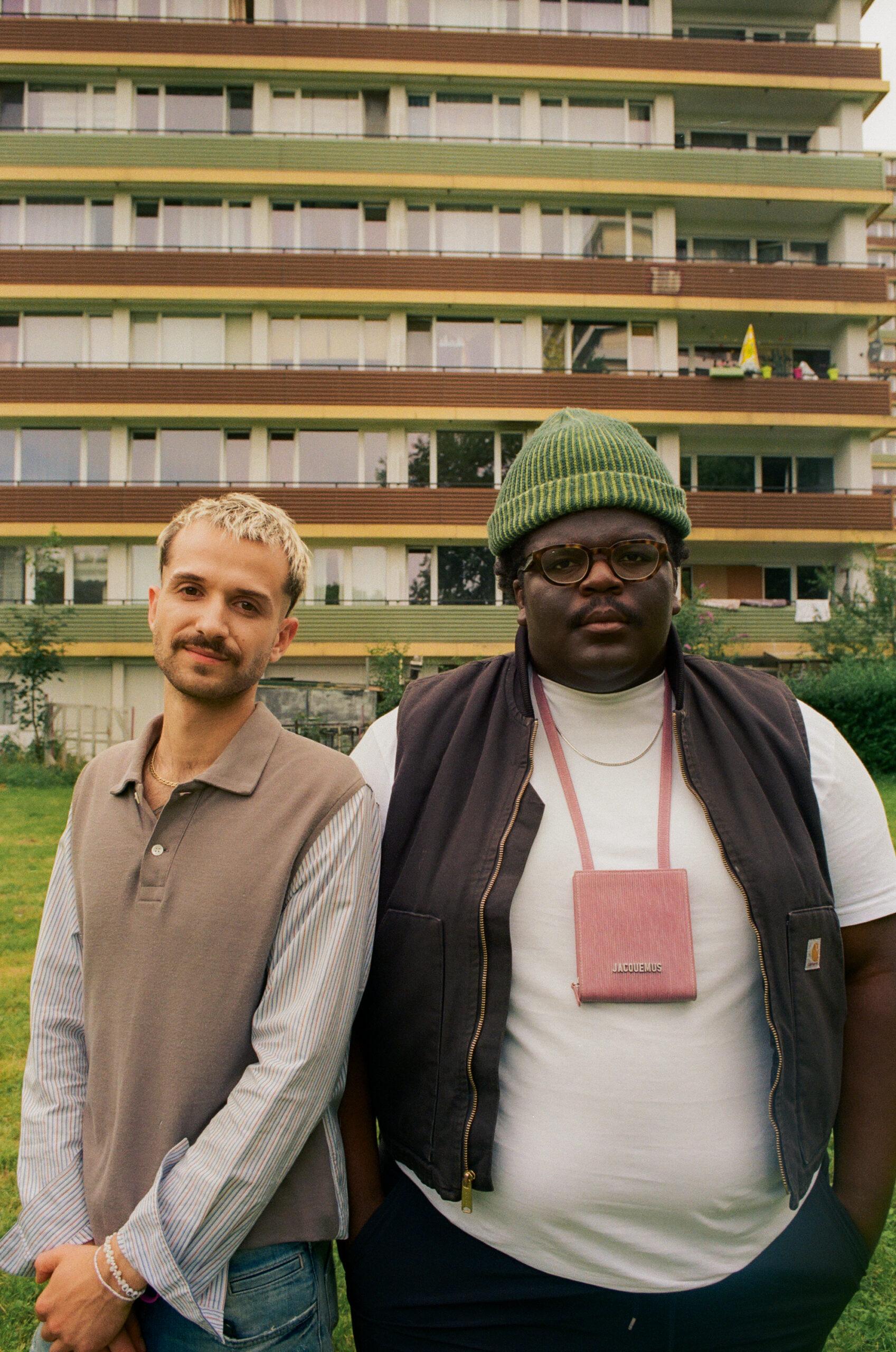 Sammy Eickmann und Rayan Djima stehen draußen vor einem Wohnhaus.