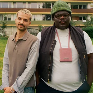 Sammy Eickmann und Rayan Djima stehen draußen vor einem Wohnhaus.