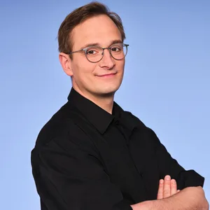 Marco Reimers steht vor einem blauen Hintergrund.