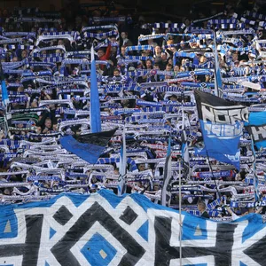HSV-Fans halten auf der Nordtribüne blaue Schals hoch