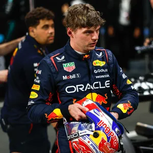 Max Verstappen in seiner Rennkleidung neben seinem Auto