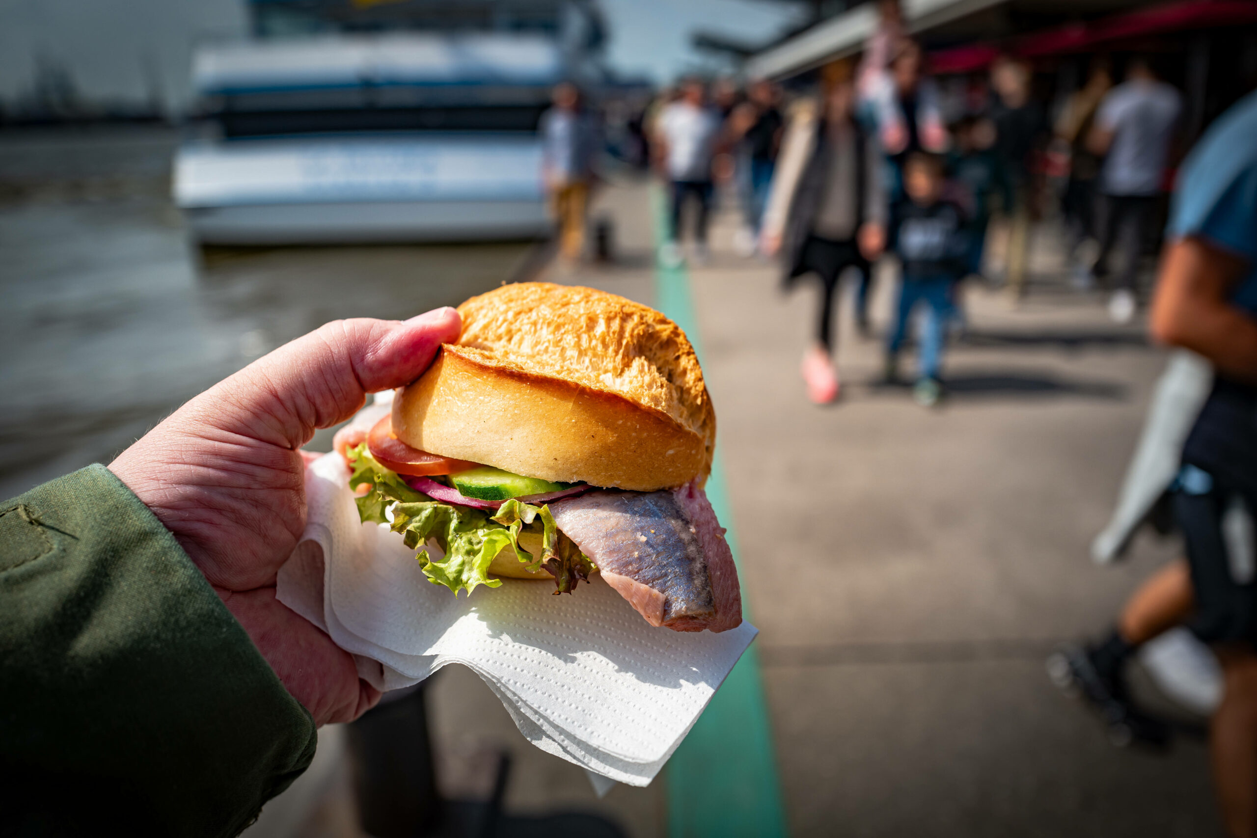 Jemand isst ein Fischbrötchen an den Hamburger Landungsbrücken.