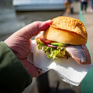Jemand isst ein Fischbrötchen an den Hamburger Landungsbrücken.