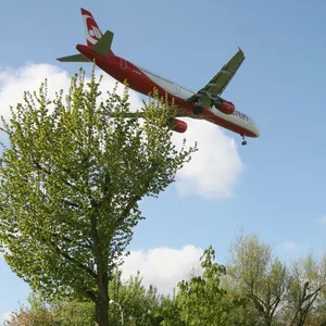 Ein Flugzeug fliegt über ein Wohnhaus hinweg.