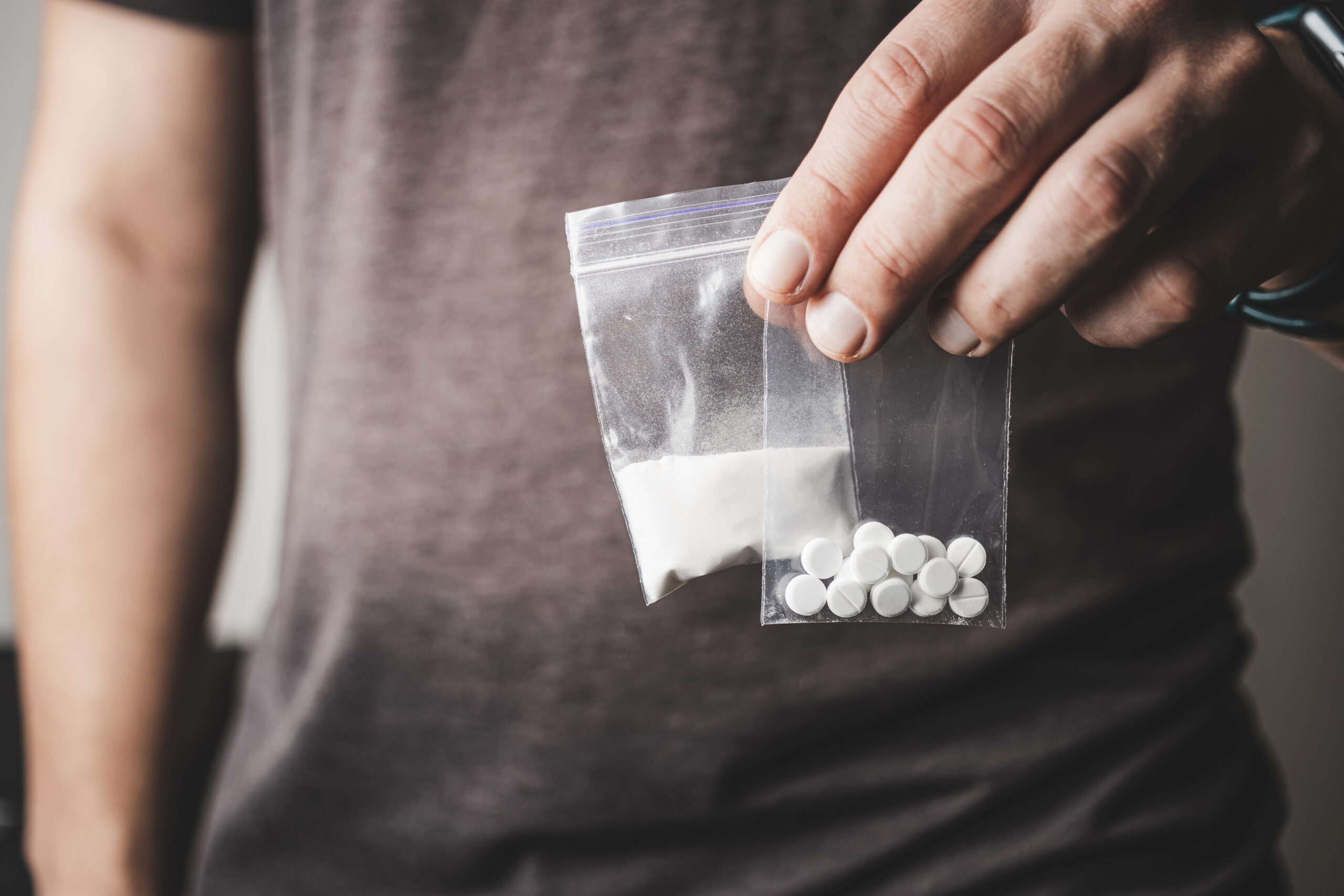 Ein Mann hält zwei Tütchen mit Drogen in der Hand. (Symbolfoto)