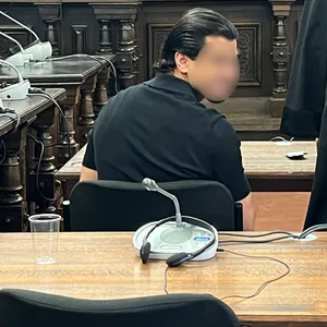 Ein Mann sitzt im Gericht und schaut nach hinten in die Kamera