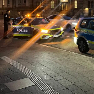 Polizeiwagen vor erleuchtetem Gebäude
