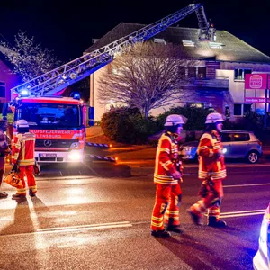 Feuerwehrkräfte im Einsatz bei einem brennenden Wohnhaus.