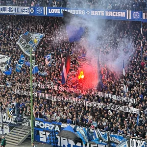 Im Volksparkstadion brennt auf der Nordtribüne ein Bengalisches Feuer. Dazu gibt es eine Botschaft der HSV-Ultras.