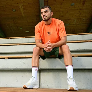 Danel Sinani sitzt auf einer Holztribüne