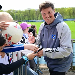 Merlin Polzin unterschreibt ein Autogramm und lächelt in die Kamera