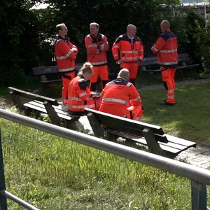 Rettungskräfte und Polizisten stehen in Övelgönne auf einer Wiese.