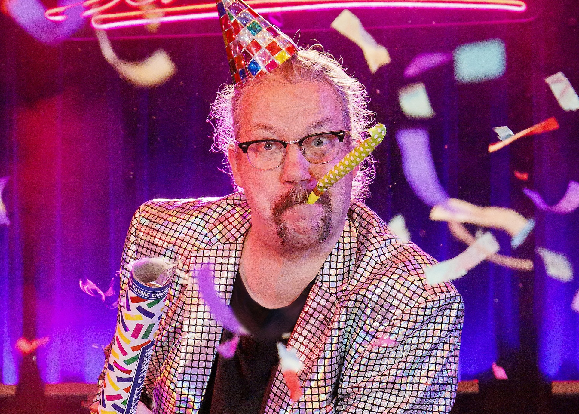 Er hat ein Partyhütchen auf dem Kopf, eine Tröte im Mund und eine Konfettikanone aus der Hand gezündet