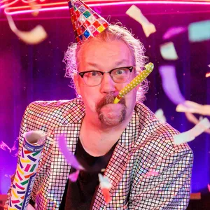 Er hat ein Partyhütchen auf dem Kopf, eine Tröte im Mund und eine Konfettikanone aus der Hand gezündet