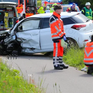Rettungskräfte stehen am Unfallort mit zwei verunfallten Autos.