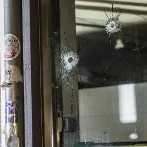 Die Einschusslöcher in der Fensterscheibe des Supermarktes