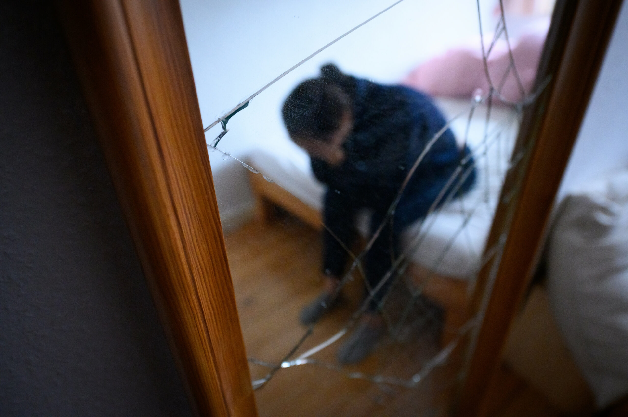 Frau sitzt mit gesenktem Kopf auf einem Bett