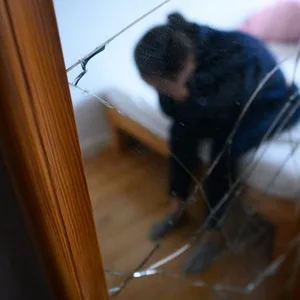 Frau sitzt mit gesenktem Kopf auf einem Bett
