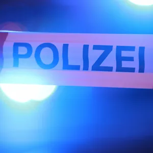 Blaulichter leuchten hinter einem Absperrband der Polizei.
