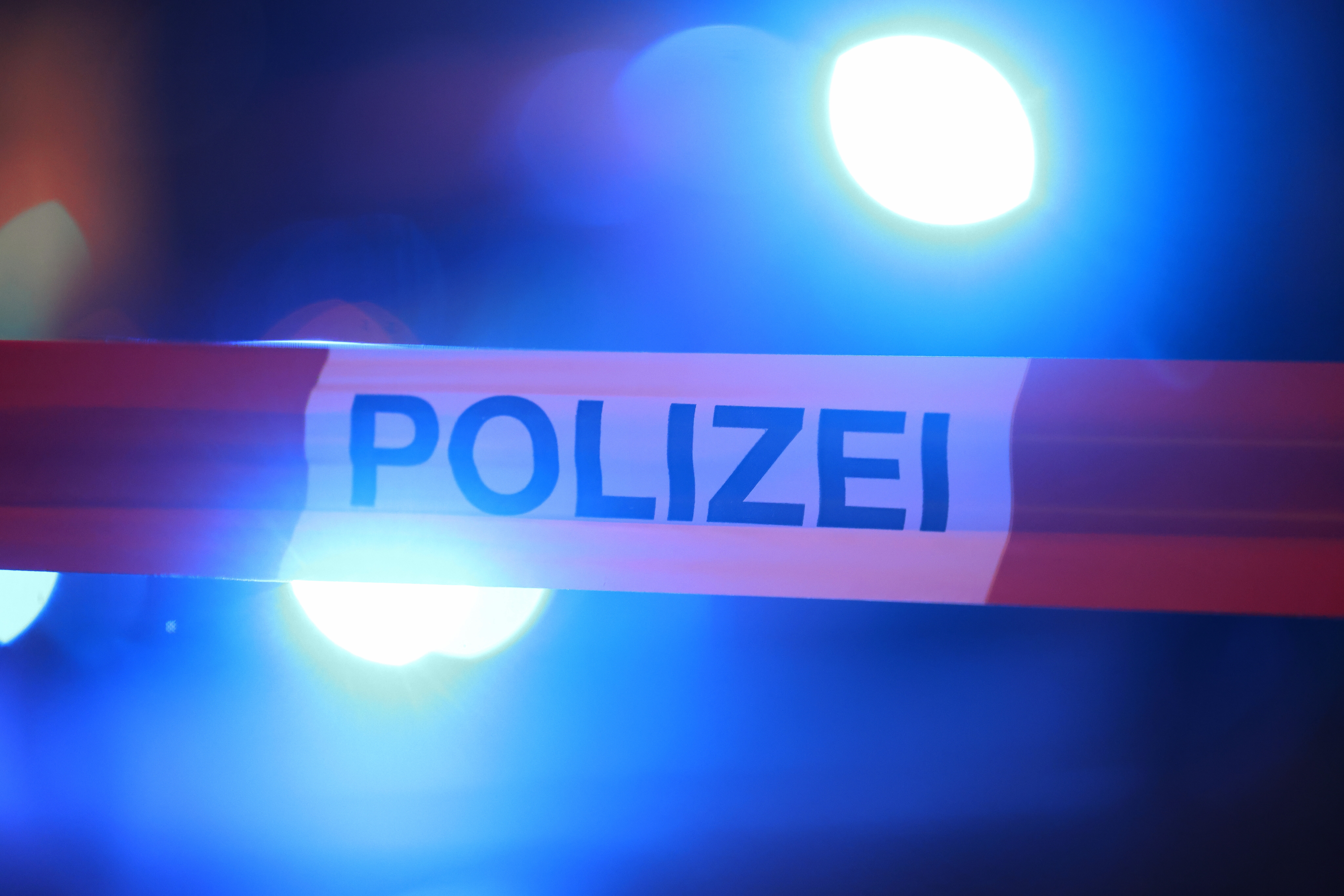 Blaulichter leuchten hinter einem Absperrband der Polizei.