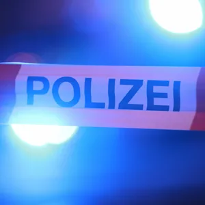 Blaulichter leuchten hinter einem Absperrband der Polizei.