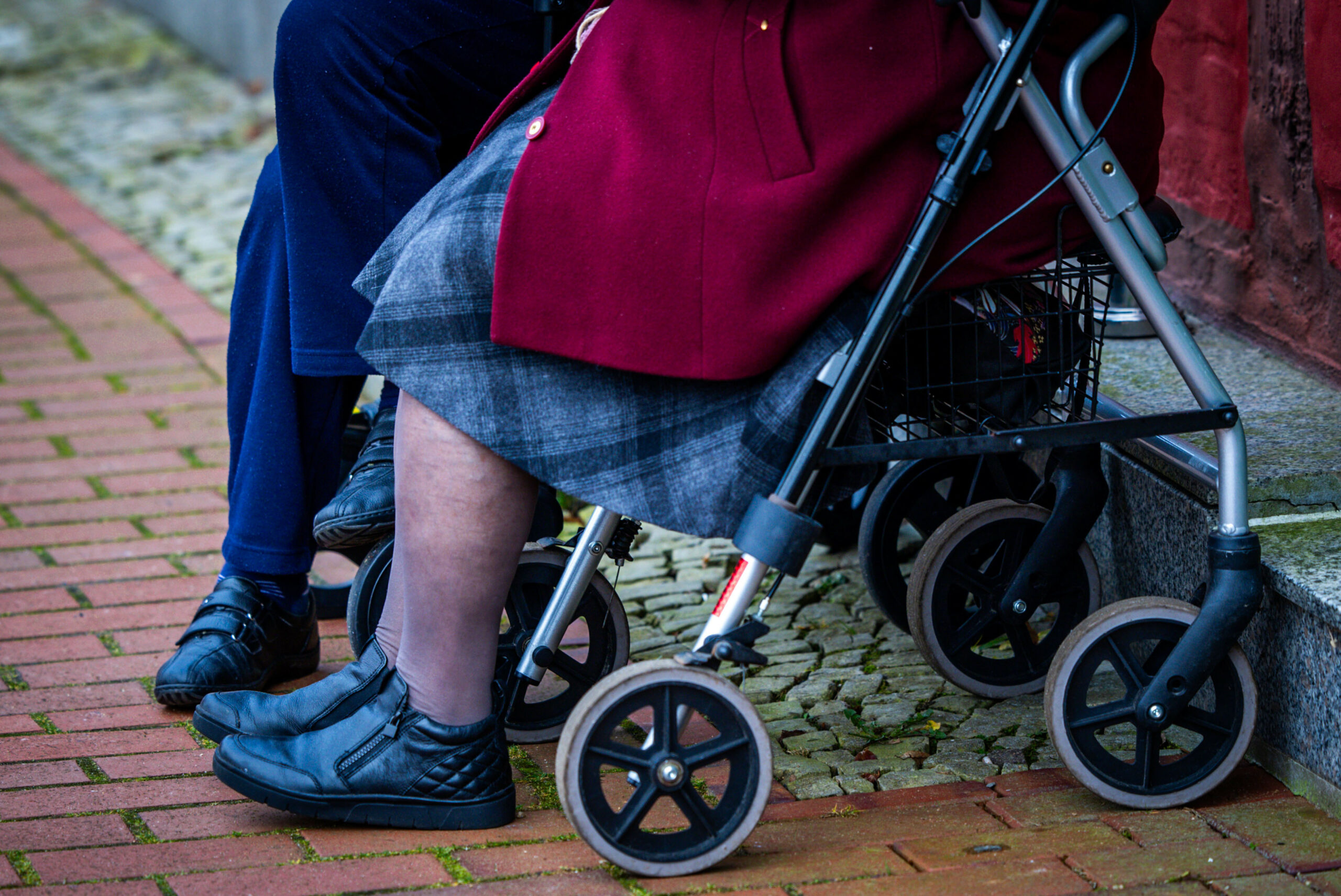 Zwei ältere Frauen sitzen auf ihrem Rollator auf dem Marktplatz.