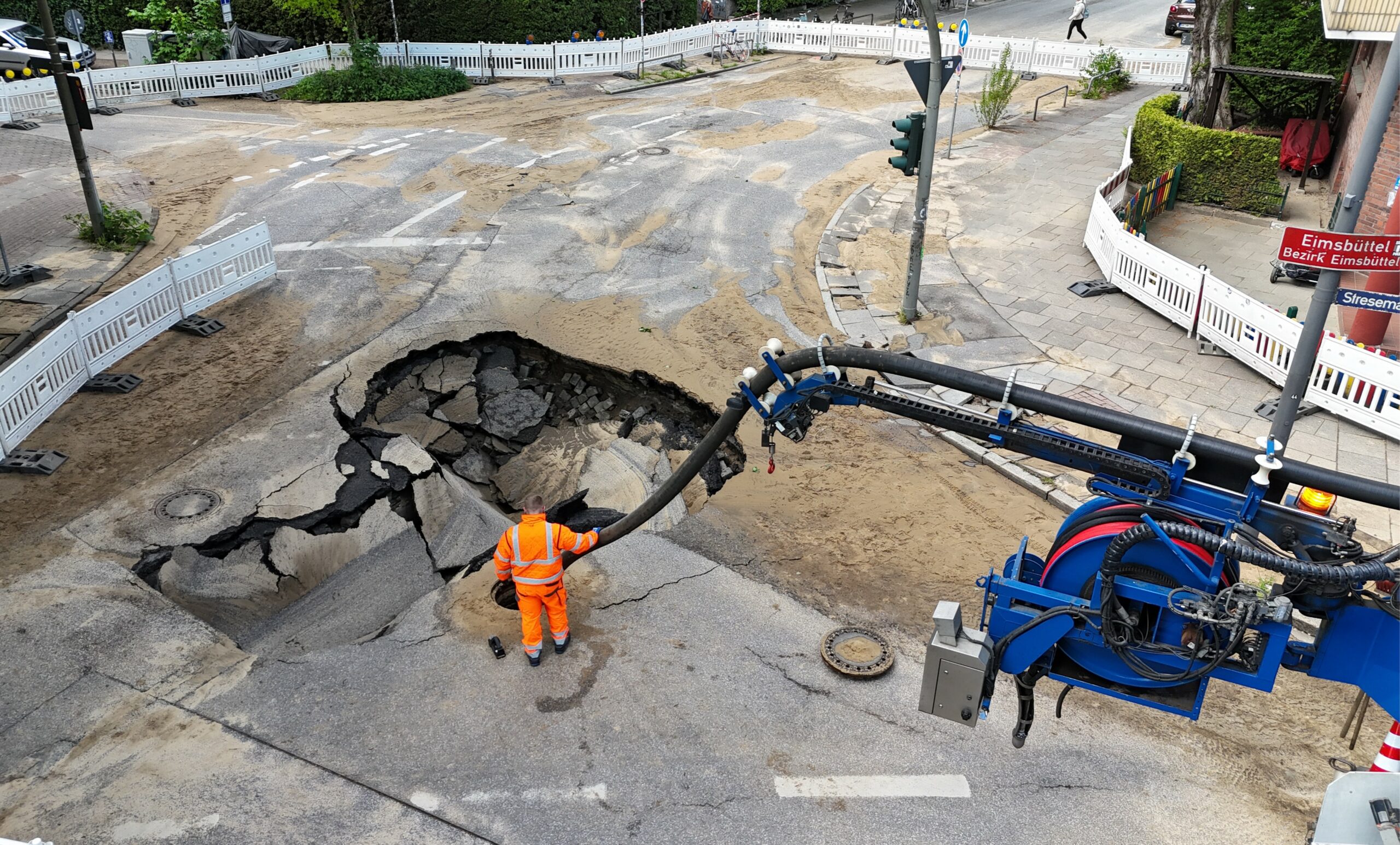 Ein riesiges Loch ist auf der Asphaltdecke der Straße am Eidelstedter Weg im Stadtteil Eimsbüttel nach einem Wasserrohrbruch zu sehen.
