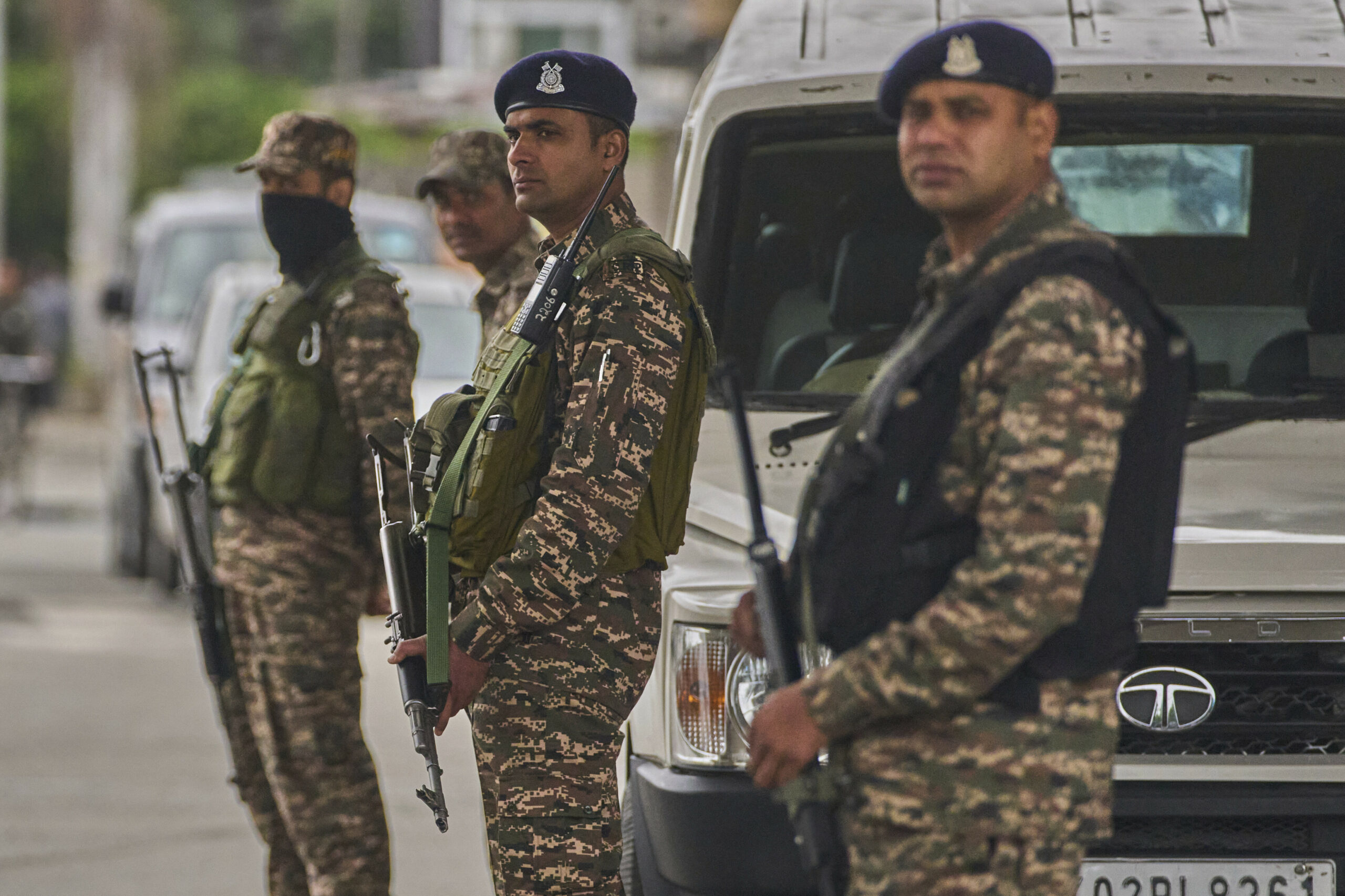 Indische paramilitärische Soldaten stehen Wache an einem provisorischen Kontrollpunkt auf einer Straße.