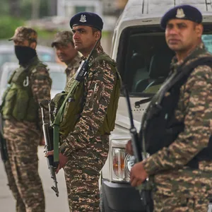 Indische paramilitärische Soldaten stehen Wache an einem provisorischen Kontrollpunkt auf einer Straße.