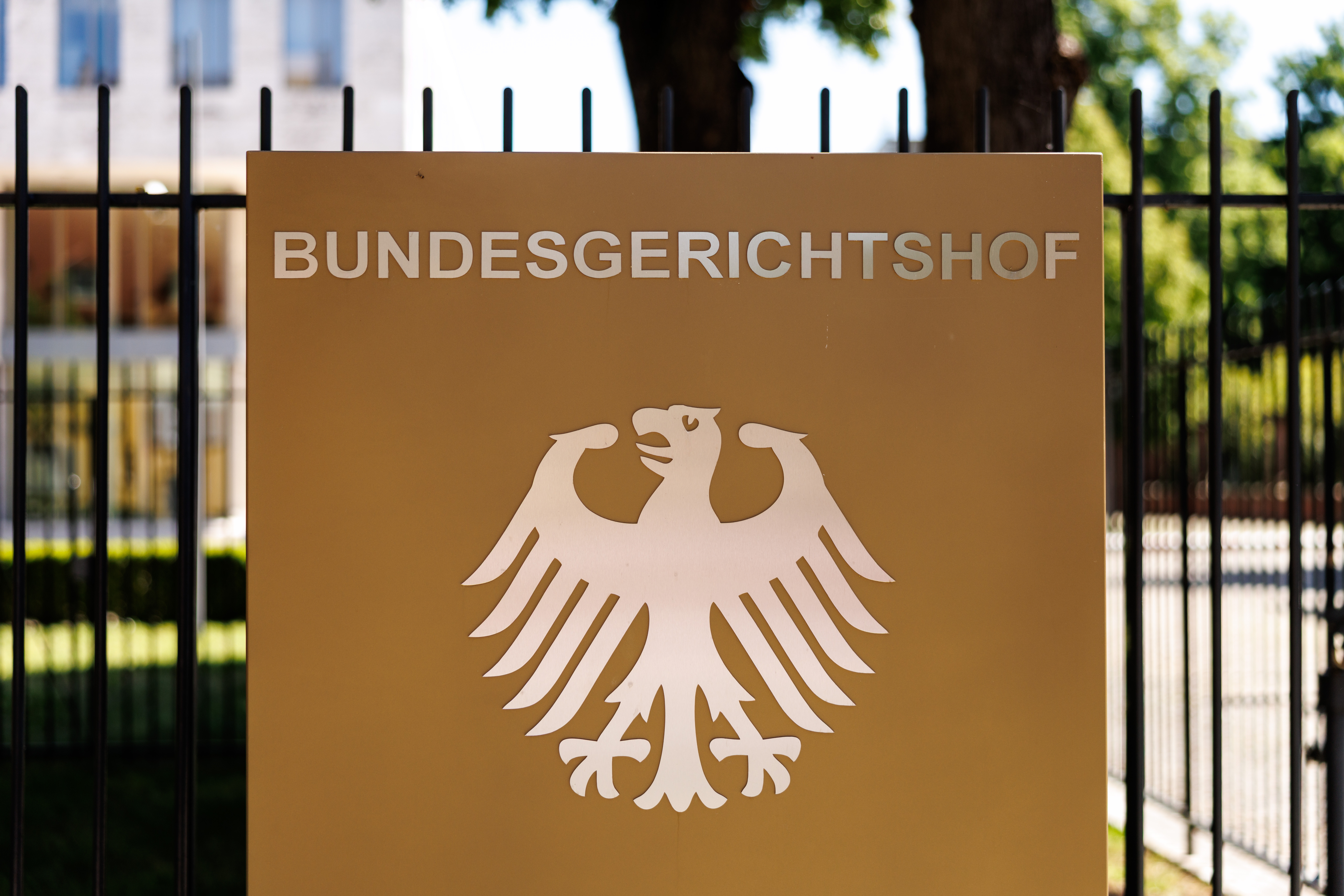 Der Schriftzug „Bundesgerichtshof“ und ein deutscher Bundesadler sind auf einer Stele an einem Zaun vor dem Hauptgebäude vom Bundesgerichtshof (BGH) in Karlsruhe (Baden-Württemberg) zu sehen.