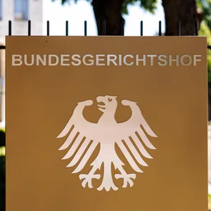 Der Schriftzug „Bundesgerichtshof“ und ein deutscher Bundesadler sind auf einer Stele an einem Zaun vor dem Hauptgebäude vom Bundesgerichtshof (BGH) in Karlsruhe (Baden-Württemberg) zu sehen.